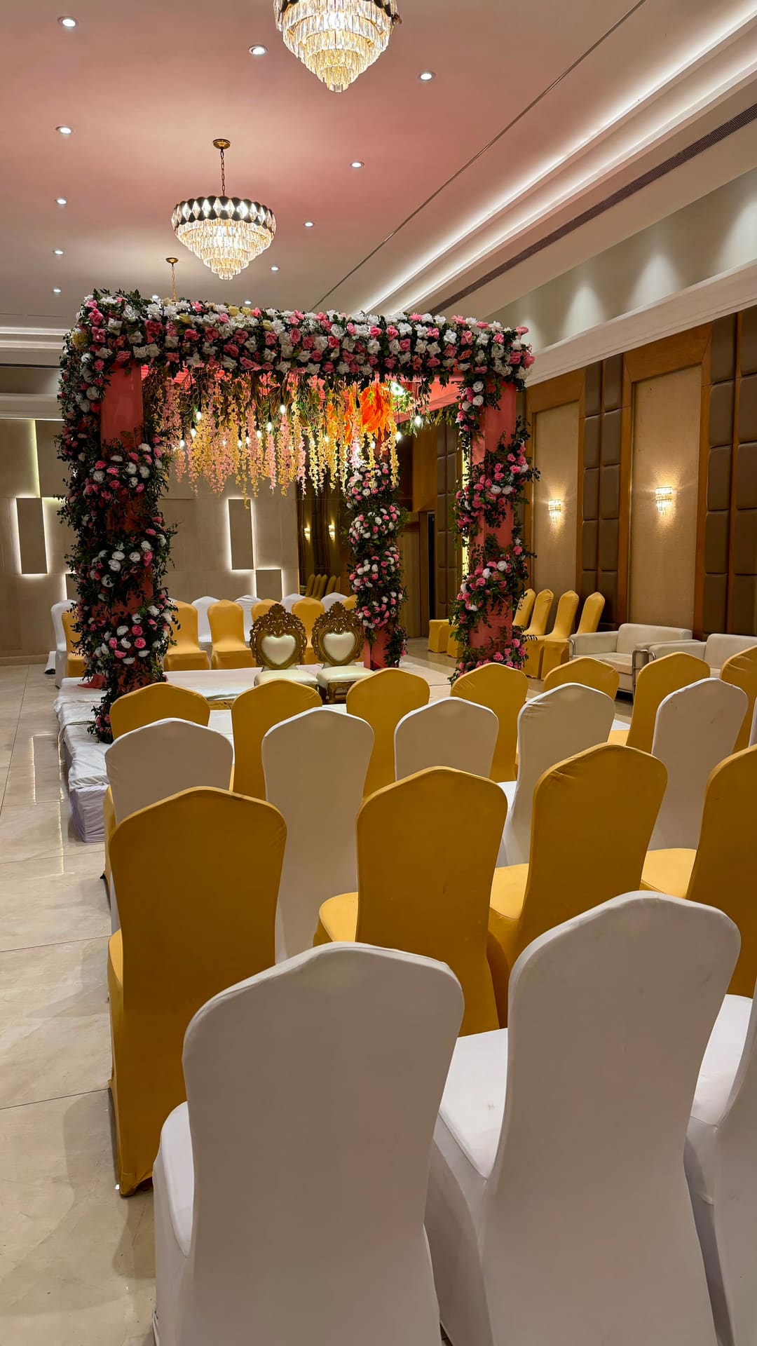 Indoor hall decorated with a floral mandap and warm chandeliers